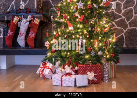Strümpfe, die an einen Kamin neben einem Weihnachtsbaum hängen am Weihnachtsmorgen Stockfoto