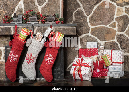 Gefüllte Strümpfe hängen an einem Kamin am Weihnachtsmorgen Stockfoto