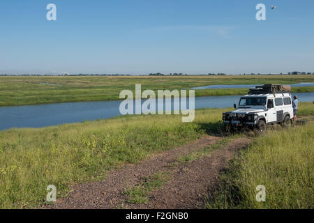 Land Rover geparkt an einem Fluss auf einer unbefestigten Straße in Botswana, Afrika Stockfoto