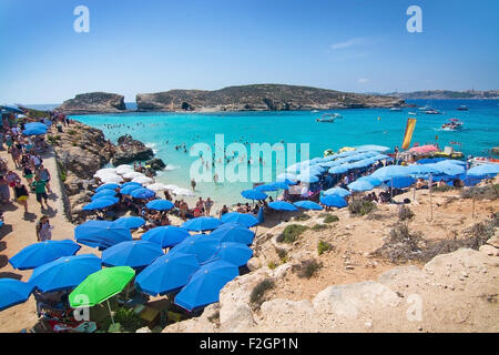 Besucher-Publikum, das klare türkisfarbene Wasser in der blauen Lagune unter Sonnenschirmen an einem sonnigen Tag im September zu genießen. Stockfoto