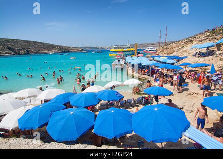 Besucher-Publikum, das klare türkisfarbene Wasser in der blauen Lagune unter Sonnenschirmen an einem sonnigen Tag im September zu genießen. Stockfoto