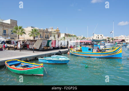 Bunt bemalt kleine hölzerne Boote vertäut im klaren, türkisfarbenen Wasser des Fischerdorf an einem sonnigen Tag im September. Stockfoto