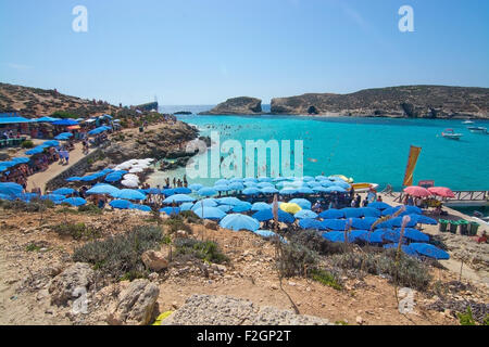 Besucher-Publikum, das klare türkisfarbene Wasser in der blauen Lagune unter Sonnenschirmen an einem sonnigen Tag im September zu genießen. Stockfoto