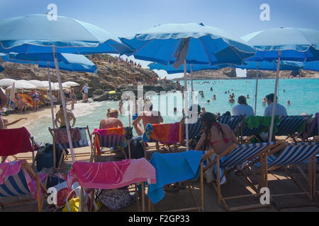 Besucher-Publikum, das klare türkisfarbene Wasser in der blauen Lagune unter Sonnenschirmen an einem sonnigen Tag im September zu genießen. Stockfoto