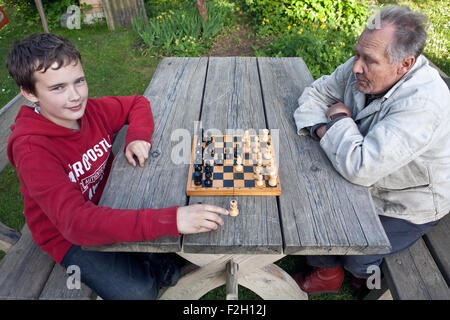 Großvater und Boy spielen Schach im Garten Stockfoto