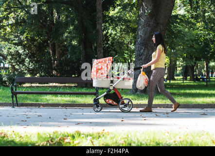 Mutter mit Kinderwagen im Park spazieren. Sonnigen Tag Stockfoto