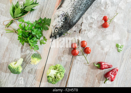 Roher Lachs Fisch in Eis und Gemüse auf weißen Tisch. Backpapier Stockfoto