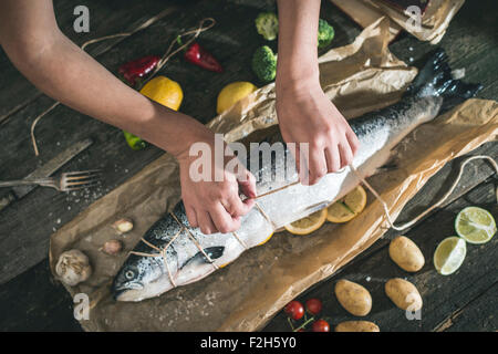 Binden ein Seil auf Fisch zum Grillen. Backpapier Stockfoto