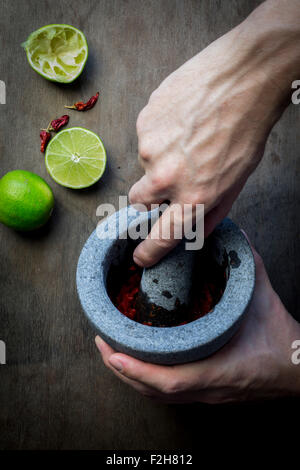 Die Hand des Mannes mit Mörser und Stößel Zubereitung Gewürz-Paste. Ansicht von oben Stockfoto