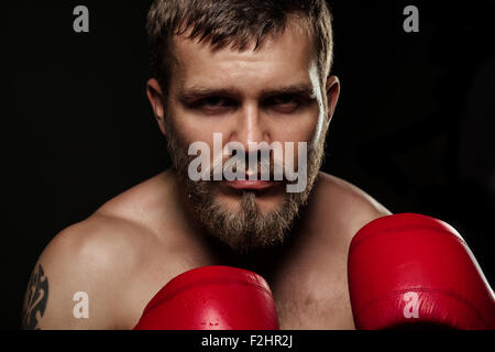 Athletische bärtigen Boxer mit Handschuhen auf dunklem Hintergrund Stockfoto