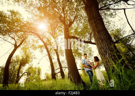 Mann und eine Frau mit einem Baby auf dem Arm in einem Sommer Wald im sonnigen Tag Stockfoto