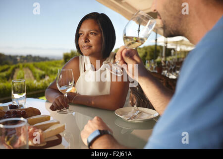Junge Frau mit einem Mann, Wein zu trinken. Paar im Urlaub in Outdoor-Wein-Bar-Restaurant von einem Weinberg.