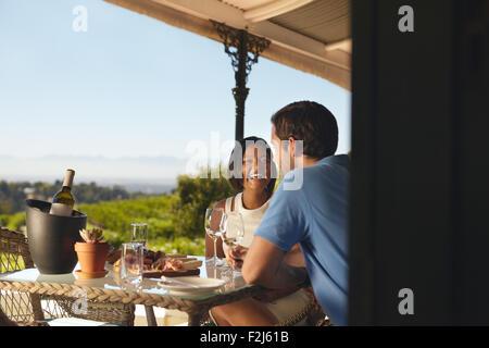 Junges Paar im Urlaub trinken Wein in einem Restaurant in Landschaft. Lächelnde junge Frau mit ihrem Freund in einem Weingut restau Stockfoto
