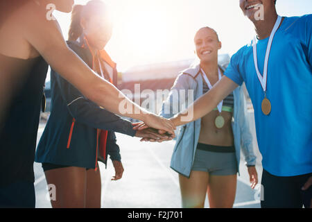 Aufnahme einer Gruppe von jungen Sportlern mit Medaillen häufen ihren Händen stehend in ein Wirrwarr. Erfolgreiches Team Athleten mit t Stockfoto