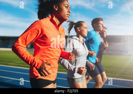 Junge afrikanische Frau mit ihrem Team auf der Laufstrecke im Stadion ausgeführt. Multiethnischen Team des Läufers auf Leichtathletik Stadiu üben Stockfoto