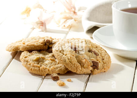 Nahaufnahme der leckere knusprige Kekse mit Schokolade und Macadamia-Nüssen auf einem weißen Holztisch Stockfoto