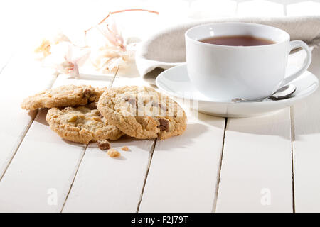 Knusprige Kekse mit Schokolade und Nüssen auf einem weißen Holztisch Stockfoto