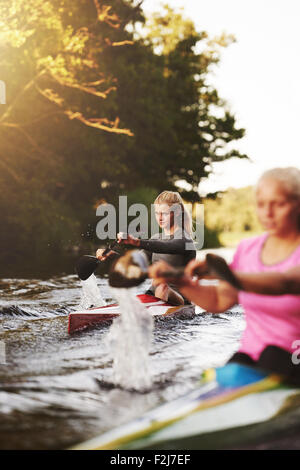 Zwei Frauen Rennen in Kajaks an einem See Stockfoto