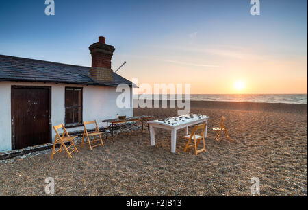 Ein Tisch und Stühle bei Sonnenaufgang am Strand von Aldeburgh in Suffolk Stockfoto