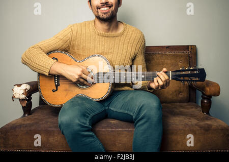 Glücklich Jüngling Gitarrenspiel auf sofa Stockfoto