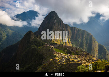 Machu Picchu, von den ersten Sonnenstrahlen, die sich aus der Öffnung Wolken beleuchtet. Die Inka-Stadt ist die meistbesuchte Reise de Stockfoto