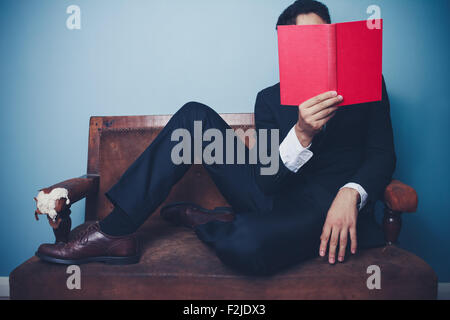 Junger Geschäftsmann lesen auf sofa Stockfoto