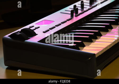 Deatil von einem MIDI-Keyboard mit Modulationsrad, beleuchtet von einem Computer-Bildschirm. Stockfoto