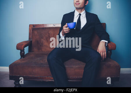 Geschäftsmann auf Sofa mit Tasse Kaffee Stockfoto