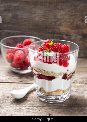 Käsekuchen mit Himbeeren, Minze im Glas auf alten hölzernen Hintergrund Stockfoto