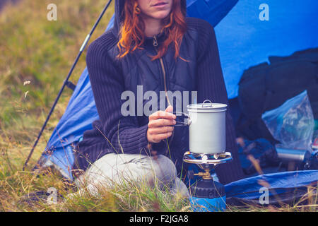 Junge Frau im Zelt kochen mit camping Kocher Stockfoto