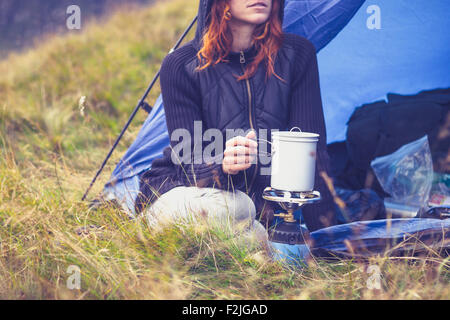 Junge Frau im Zelt kochen mit camping Kocher Stockfoto