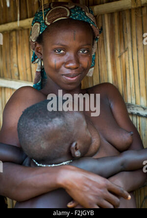 Benin, Westafrika, Onigbolo Isaba, Holi Stamm Frau mit traditionellen Gesichts-Tätowierungen und Narben hält ihr Baby bedeckt Stockfoto