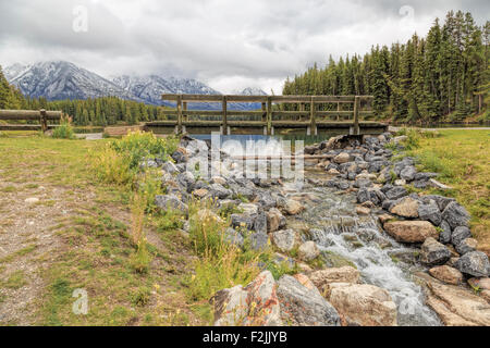 Gebirgsbach fließt von Johnson See mit Steg, Banff Nationalpark, Rocky Mountains, Alberta, Kanada, Nordamerika. Stockfoto