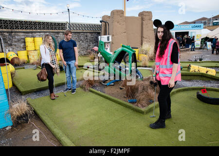 Staff Member bei Banksy Dismaland in Weston super Mare Angebot heiteren Hilfe crazy Golf Spielern auf den gepflegten greens Stockfoto