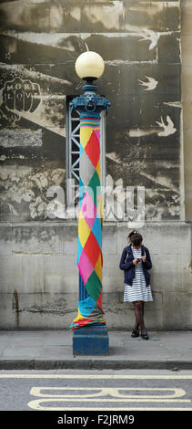 Eine junge Frau und ihr Handy neben einem fröhlich bekleidet Lampe post auf Nelson Street im Stadtzentrum von Bristol UK Stockfoto