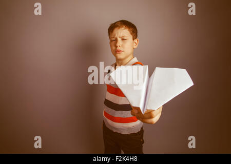 junge Teenager europäischen Erscheinungsbild Brown startet einen Papierflieger Stockfoto