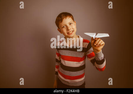 junge Teenager europäischen Erscheinungsbild Brown startet einen Papierflieger Stockfoto