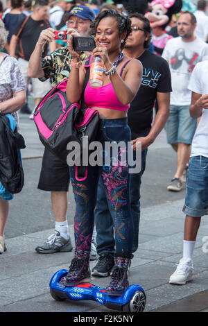 Eine Frau nimmt ein Bild während der Fahrt eine Keystone Zauberei selbstbalancierende Schalttafel auf dem Times Square in New York City. Stockfoto