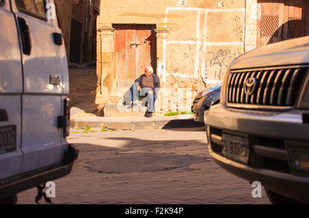 LEONFORTE, Italien - Januar, 08: Alter Mann sitzt auf der Schritt der alten Tür-am 8. Januar 2014 Stockfoto