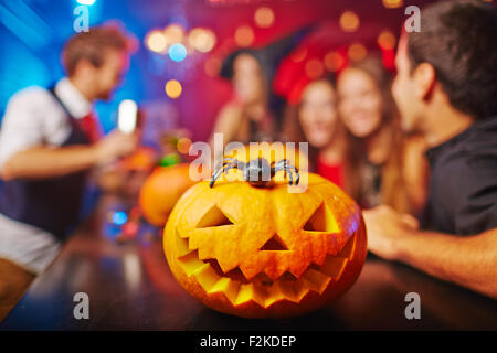 Geschnitzte Kürbis und Spinne auf Hintergrund der Gruppe von Freunden Halloween feiern in der Bar Stockfoto