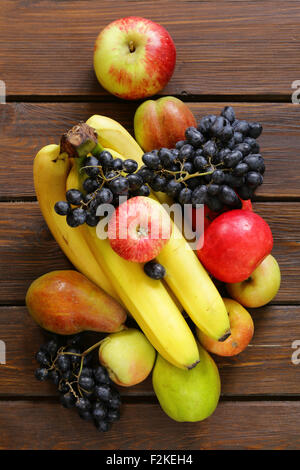 verschiedene Früchte (Äpfel, Birnen, Bananen, Trauben) auf einem hölzernen Hintergrund Stockfoto