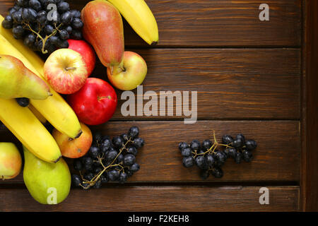 verschiedene Früchte (Äpfel, Birnen, Bananen, Trauben) auf einem hölzernen Hintergrund Stockfoto