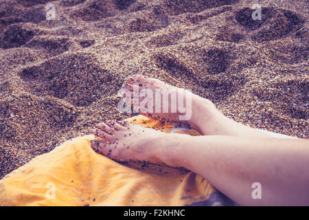 Frauenbeine auf Handtuch am Strand Stockfoto