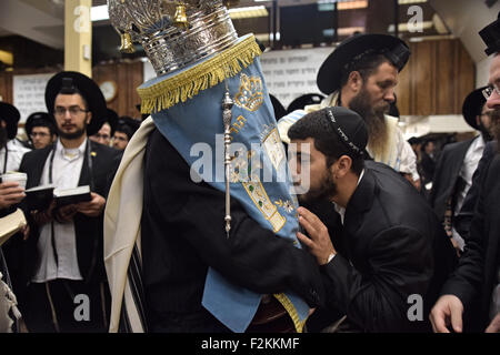 Ein religiösen jüdischer Mann küsst die Thora, als es an die Heilige Lade, während der Morgen Synagoge Gottesdienste in Brooklyn, NYC zurückgegeben wird Stockfoto