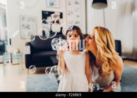 Glückliche Mutter mit Tochter Seifenblasen zu Hause Stockfoto