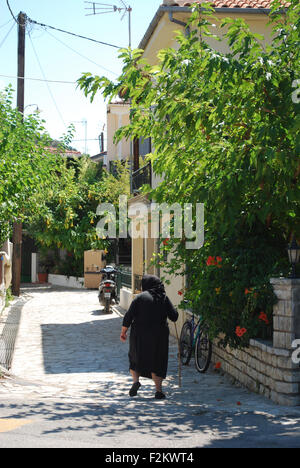 Alte griechische Frau in der traditionellen schwarzen Kleidung wandern in Vathi Bay, Meganisi, Griechenland Stockfoto