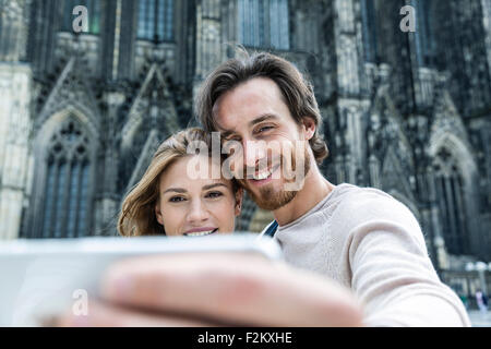 Deutschland, Köln, Porträt des jungen Paares unter ein Selfie vor Kölner Dom Stockfoto