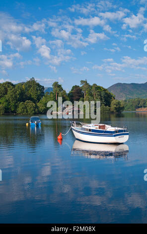 Blick auf kleine Boote vor Anker auf Derwentwater Bootshaus und Steg am bewaldeten Derwent Insel, ruhigen sonnigen Sommermorgen, Cumbria Stockfoto