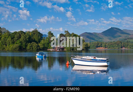 Blick auf kleine Boote vor Anker am Derwentwater bewaldeten Derwent Insel, steigt hinter Fjälls, ruhigen sonnigen Morgen, Cumbria UK Stockfoto