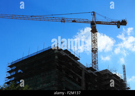 Kran und Bau Website Silhouette gegen strahlend blauer Himmel und Wolken. Stockfoto